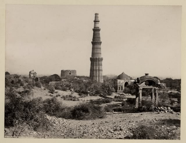 A wide archival view of the Qutub Complex, with Qutub Minar rising above the ruins